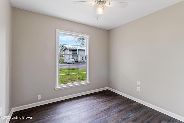 spare room featuring dark wood-style flooring, baseboards, ceiling fan, and a wealth of natural light