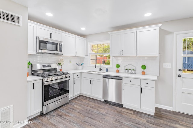kitchen featuring stainless steel appliances, visible vents, a sink, and wood finished floors