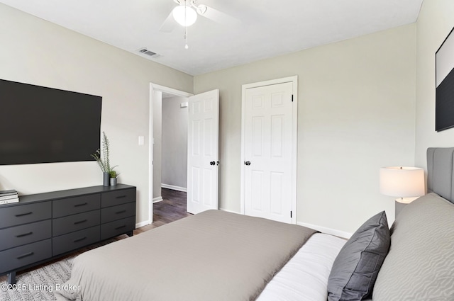 bedroom with visible vents, a ceiling fan, baseboards, and wood finished floors