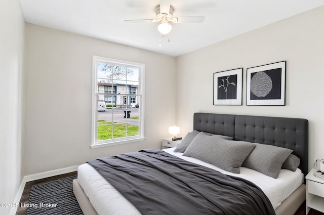 bedroom featuring ceiling fan, baseboards, multiple windows, and wood finished floors