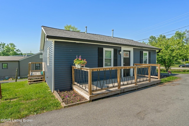 view of front facade featuring a wooden deck and roof with shingles