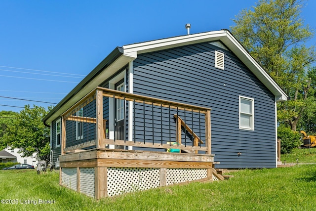 rear view of house featuring a wooden deck and a yard