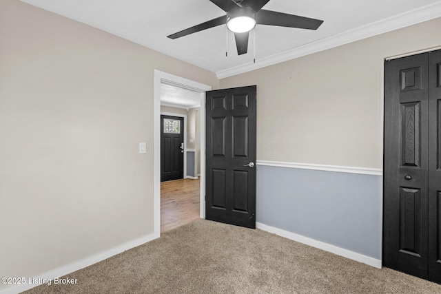 unfurnished bedroom with baseboards, carpet floors, ornamental molding, and ceiling fan