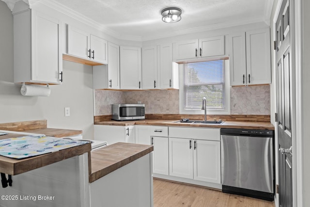 kitchen featuring butcher block countertops, appliances with stainless steel finishes, a sink, white cabinets, and light wood-style floors