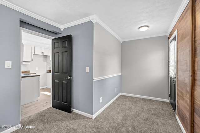 unfurnished room with crown molding, light carpet, a textured ceiling, and baseboards