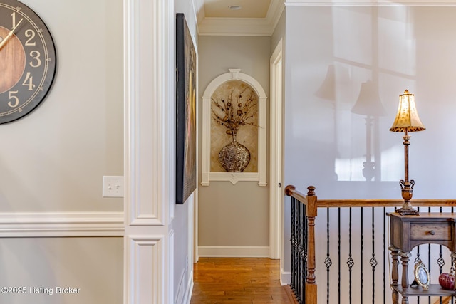 hall featuring baseboards, wood finished floors, and ornamental molding