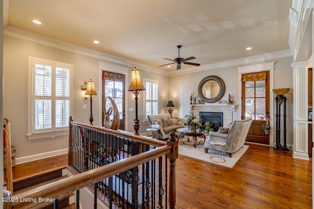 living room with plenty of natural light, a ceiling fan, dark wood-style floors, and a glass covered fireplace