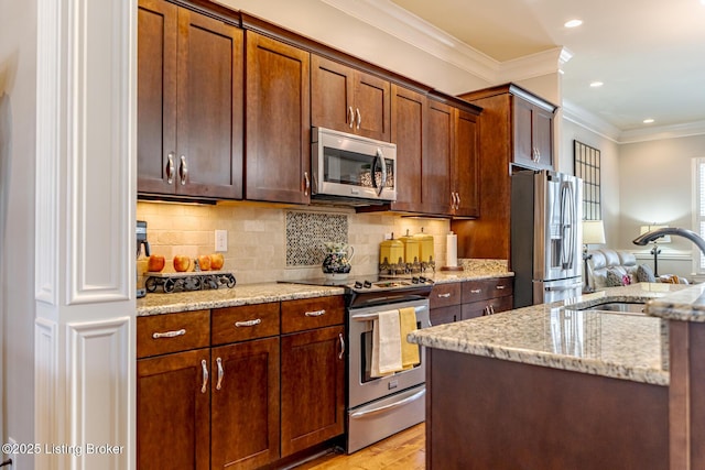 kitchen with stainless steel appliances, light wood-style flooring, a sink, light stone counters, and crown molding