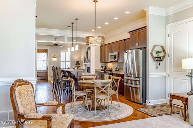 dining area with dark wood finished floors, crown molding, a ceiling fan, and recessed lighting