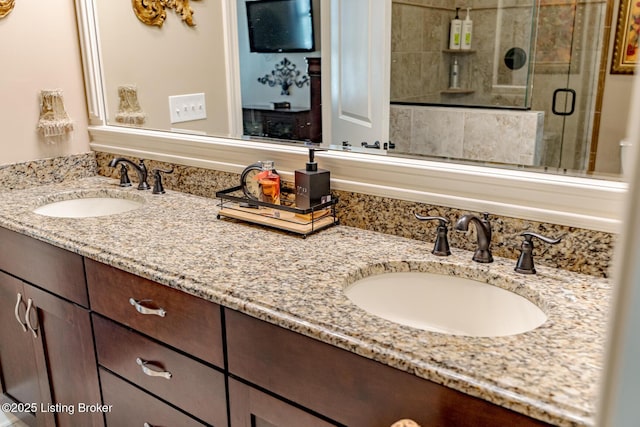 full bath with a sink, double vanity, and a stall shower