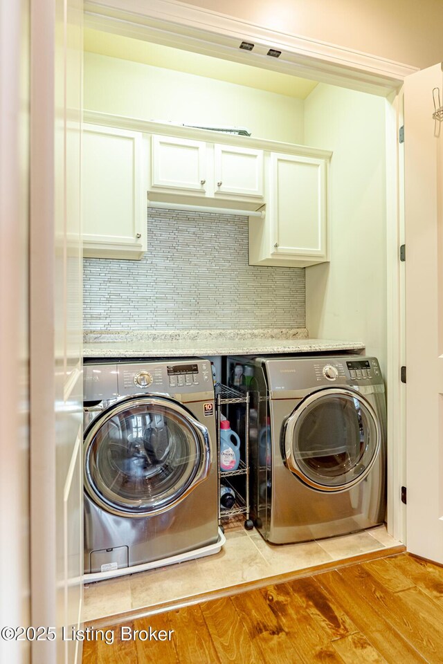 clothes washing area featuring wood finished floors, washing machine and clothes dryer, and laundry area