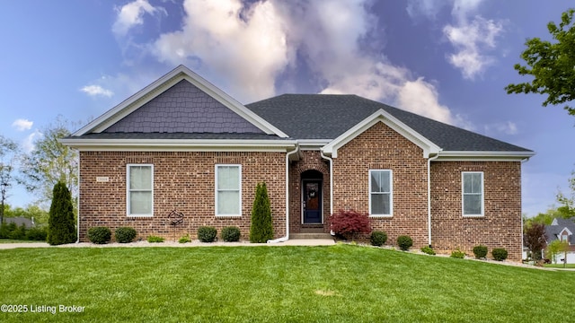view of front of home with roof with shingles, a front lawn, and brick siding