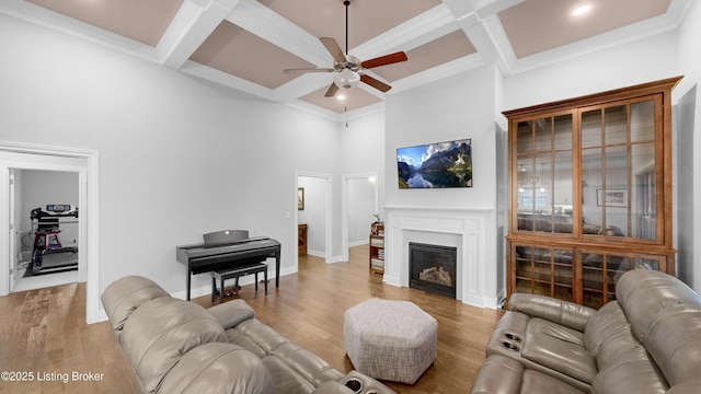 living area featuring beam ceiling, wood finished floors, a ceiling fan, and coffered ceiling