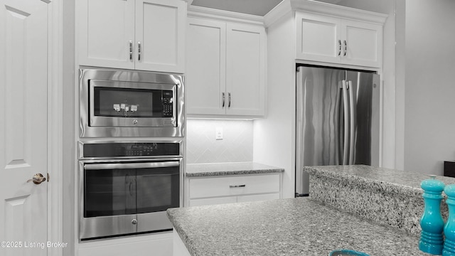 kitchen featuring light stone counters, tasteful backsplash, white cabinetry, and stainless steel appliances