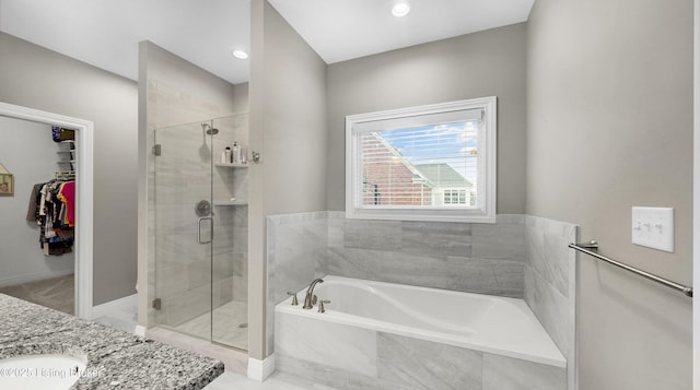 full bathroom with a spacious closet, a shower stall, a bath, and vanity