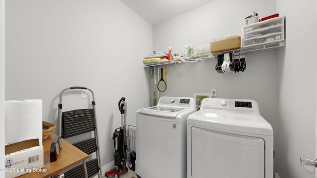 clothes washing area with independent washer and dryer, laundry area, and baseboards