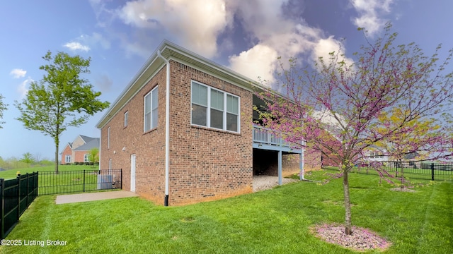 view of side of home featuring a lawn, a fenced backyard, and brick siding