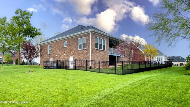 back of property featuring brick siding, a yard, a balcony, and fence