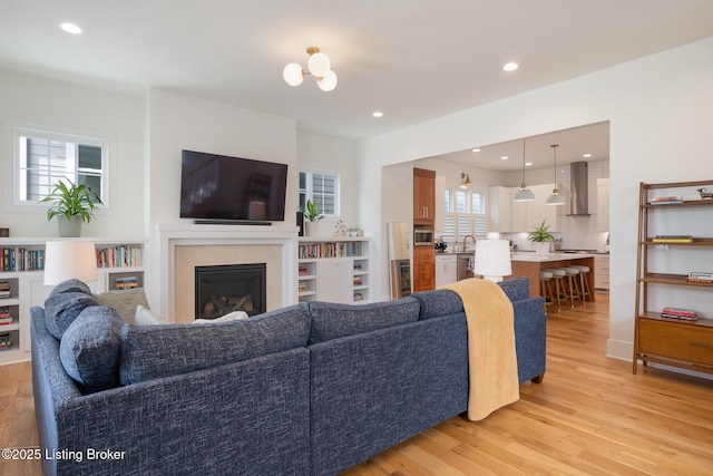 living area featuring a glass covered fireplace, recessed lighting, and light wood-style floors