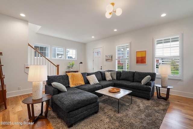 living room with plenty of natural light, light wood-style floors, and stairway
