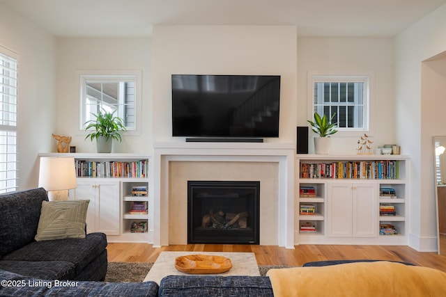 living room featuring a glass covered fireplace and wood finished floors