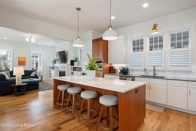 kitchen featuring a center island, light wood-style flooring, a sink, and a kitchen bar