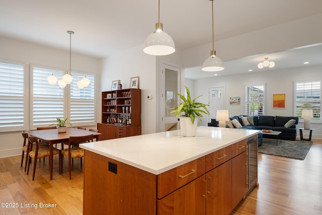 kitchen with a center island, pendant lighting, beverage cooler, and light wood-style floors