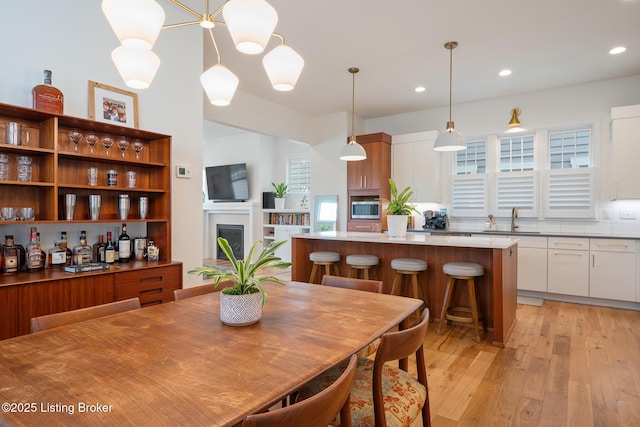 dining room featuring a fireplace, recessed lighting, and light wood-type flooring