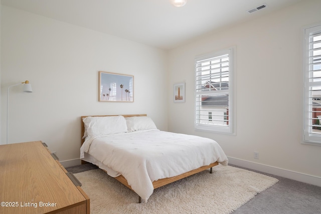 bedroom with baseboards, multiple windows, visible vents, and carpet
