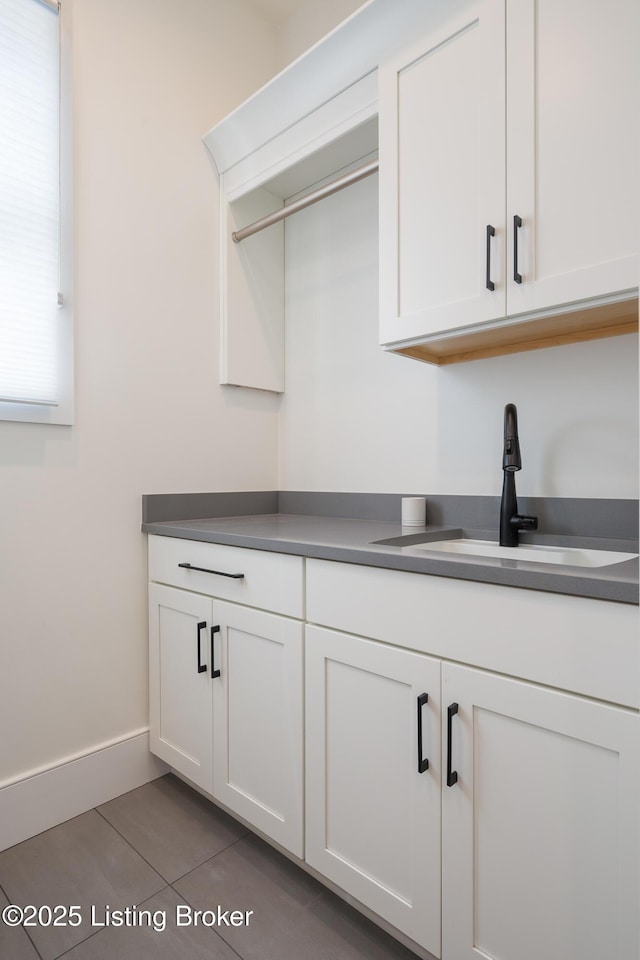 kitchen with white cabinets, dark countertops, and a sink