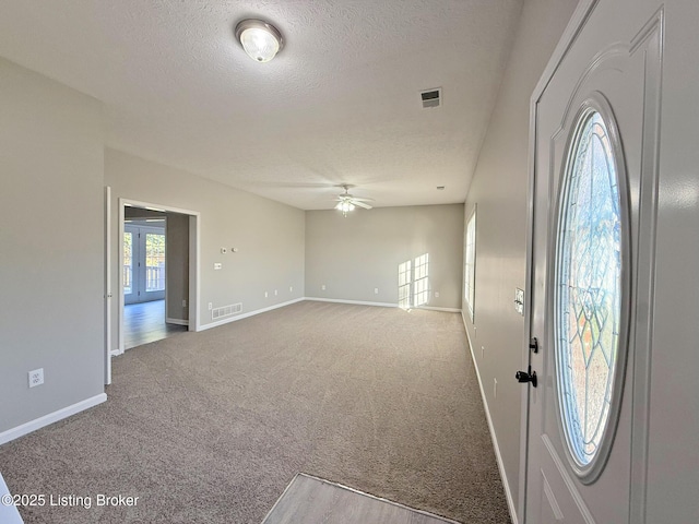 entryway with visible vents, a ceiling fan, a textured ceiling, and carpet flooring