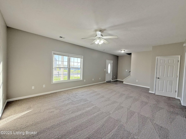 carpeted empty room with baseboards, visible vents, and a ceiling fan