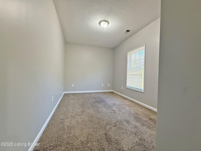 spare room with carpet floors, a textured ceiling, and baseboards