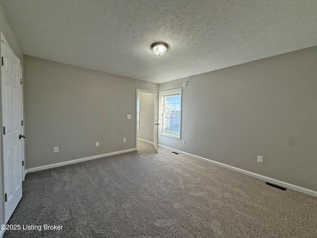 spare room featuring carpet floors, visible vents, and baseboards