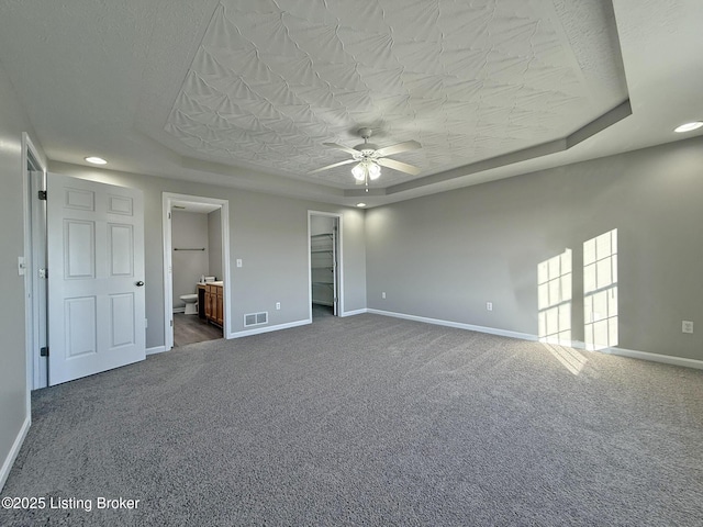unfurnished bedroom with baseboards, visible vents, carpet flooring, and a tray ceiling