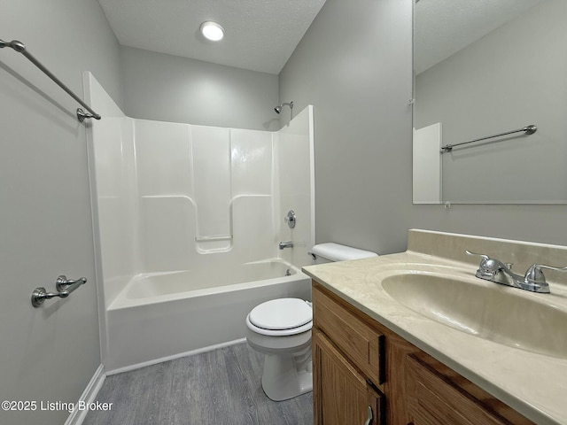 full bathroom with wood finished floors, toilet, shower / tub combination, vanity, and a textured ceiling