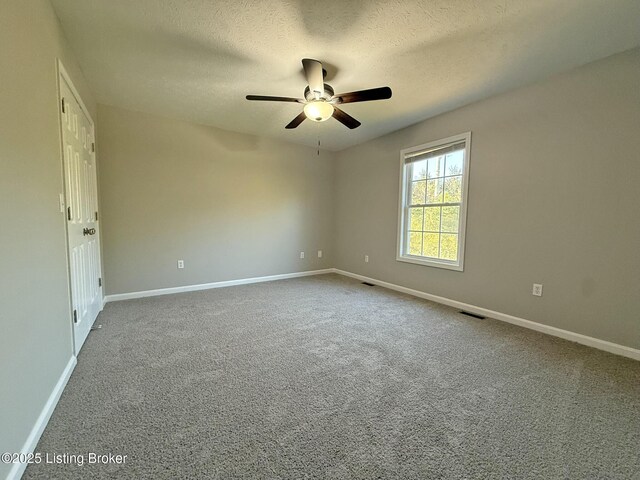 carpeted empty room with a ceiling fan, visible vents, a textured ceiling, and baseboards