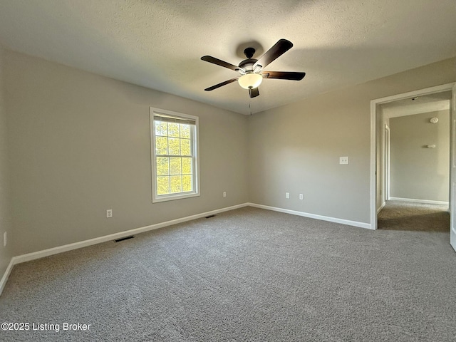 empty room featuring dark carpet, a textured ceiling, visible vents, ceiling fan, and baseboards
