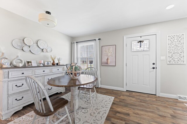 dining area featuring wood finished floors, a healthy amount of sunlight, baseboards, and visible vents