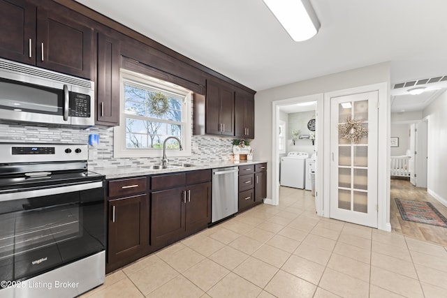 kitchen with a sink, stainless steel appliances, light countertops, visible vents, and independent washer and dryer