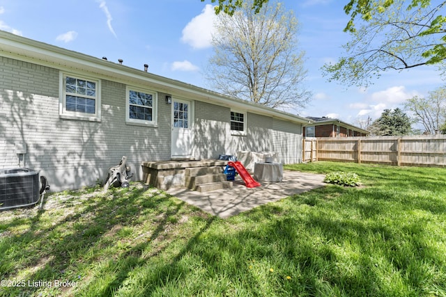 rear view of property with cooling unit, a lawn, brick siding, and fence
