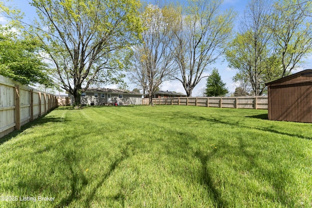 view of yard featuring a storage unit, an outbuilding, and a fenced backyard