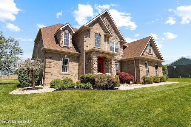 view of front of house with stone siding, brick siding, roof with shingles, and a front yard