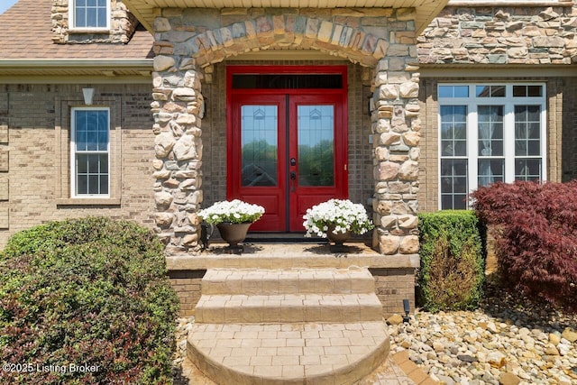 doorway to property with stone siding, brick siding, and french doors