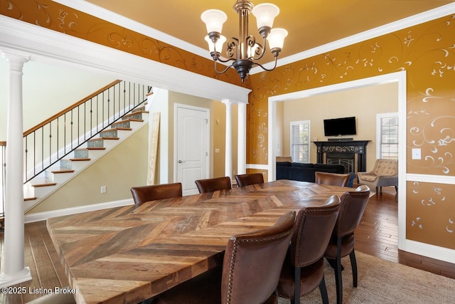 dining area with stairway, a fireplace, a chandelier, and decorative columns