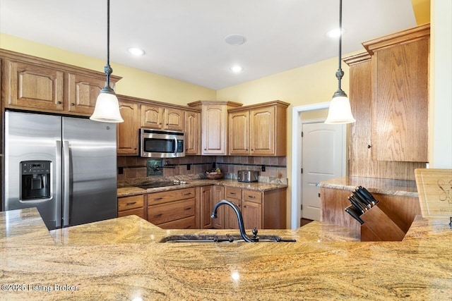 kitchen with light stone countertops, decorative light fixtures, a sink, backsplash, and appliances with stainless steel finishes