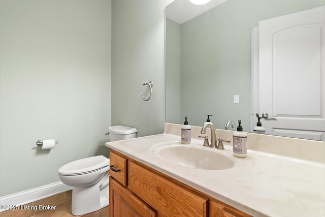 bathroom with toilet, tile patterned flooring, vanity, and baseboards