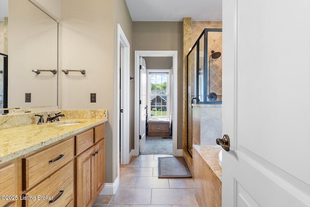 bathroom featuring tile patterned floors, vanity, baseboards, and a stall shower