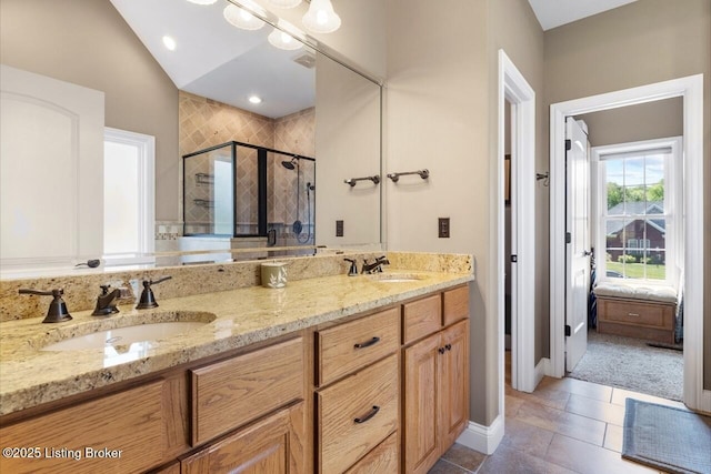 ensuite bathroom with a stall shower, lofted ceiling, double vanity, and a sink