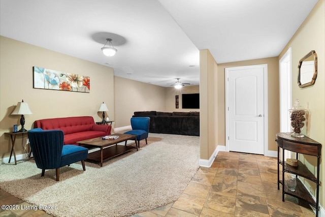 living room with ceiling fan, baseboards, and stone finish flooring